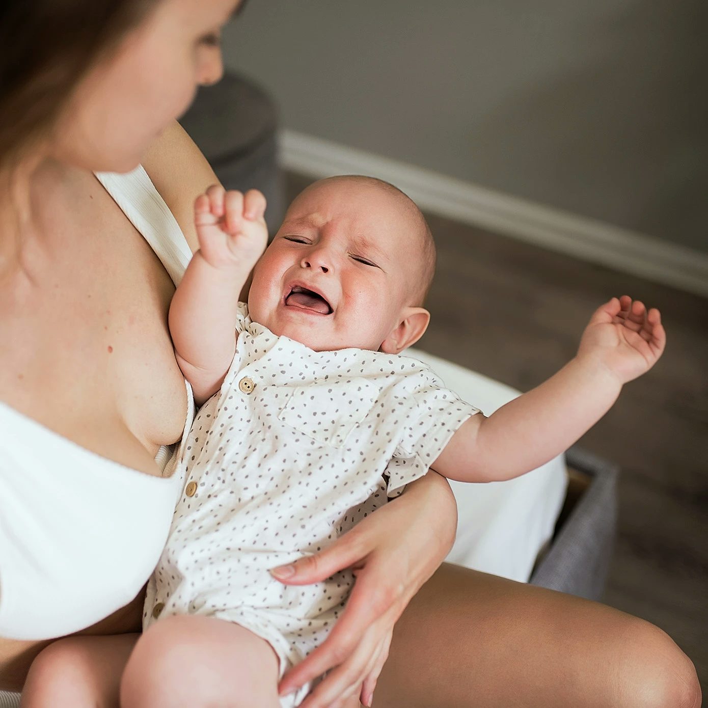 En bebis, runt 7 månader, gråter i sin mammas knä