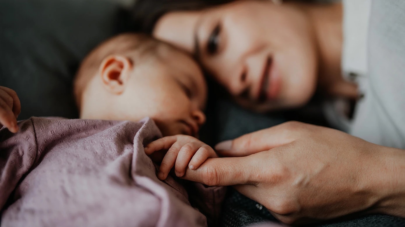 Mother holds her sleeping daughters hand