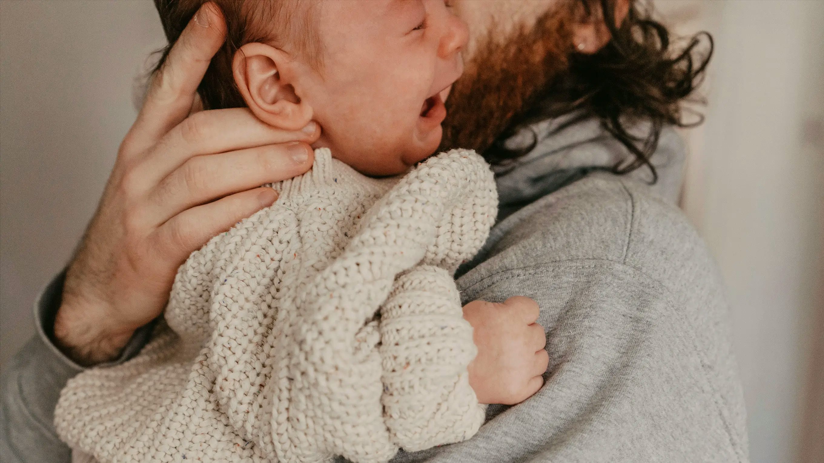 Overtired baby cries in dads arms