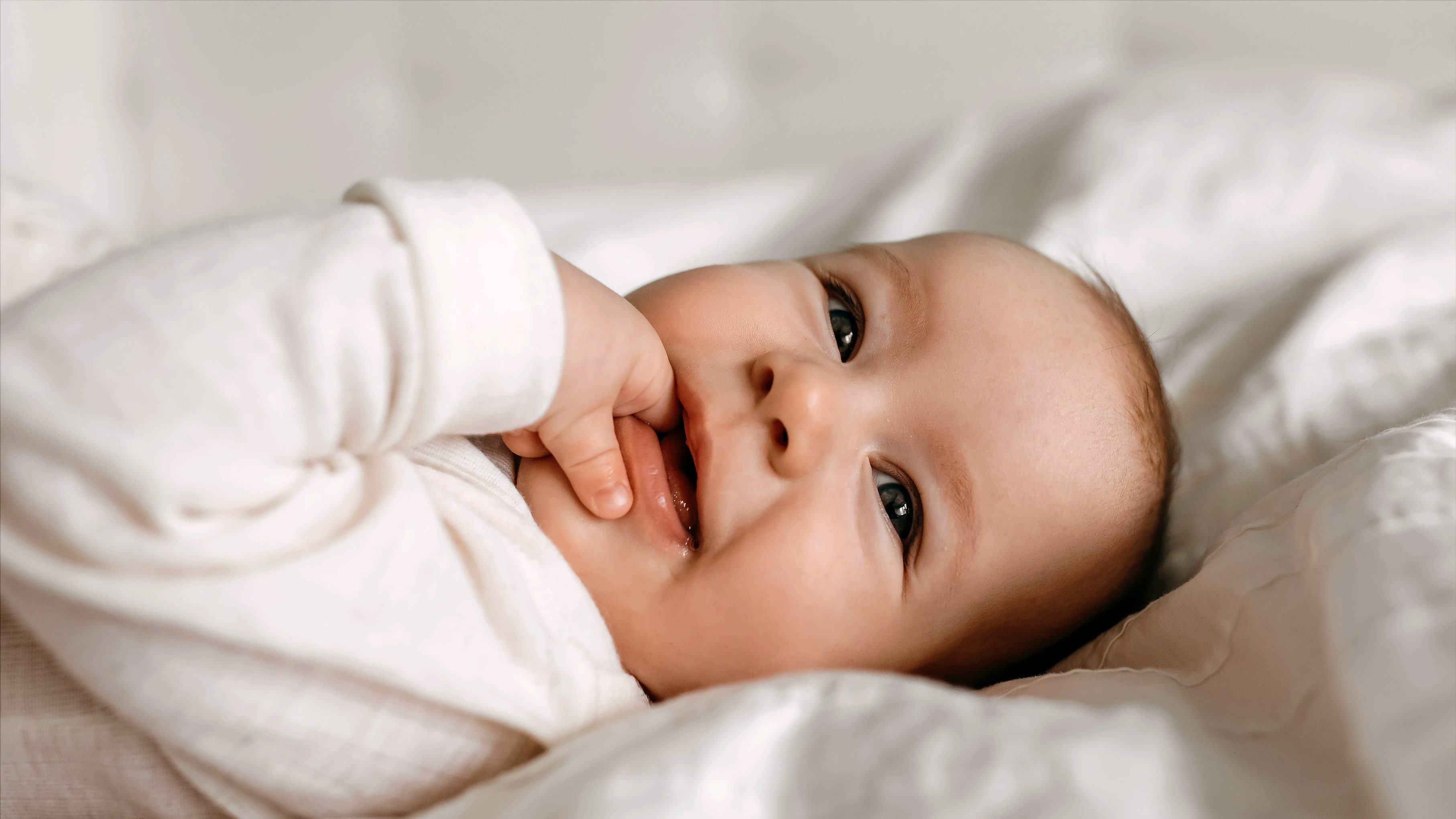 Happy baby with a hand in their mouth